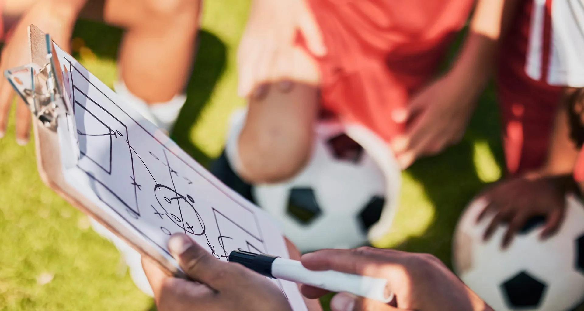 Trainer mit Taktiktafel vor jungen Fussballspielern